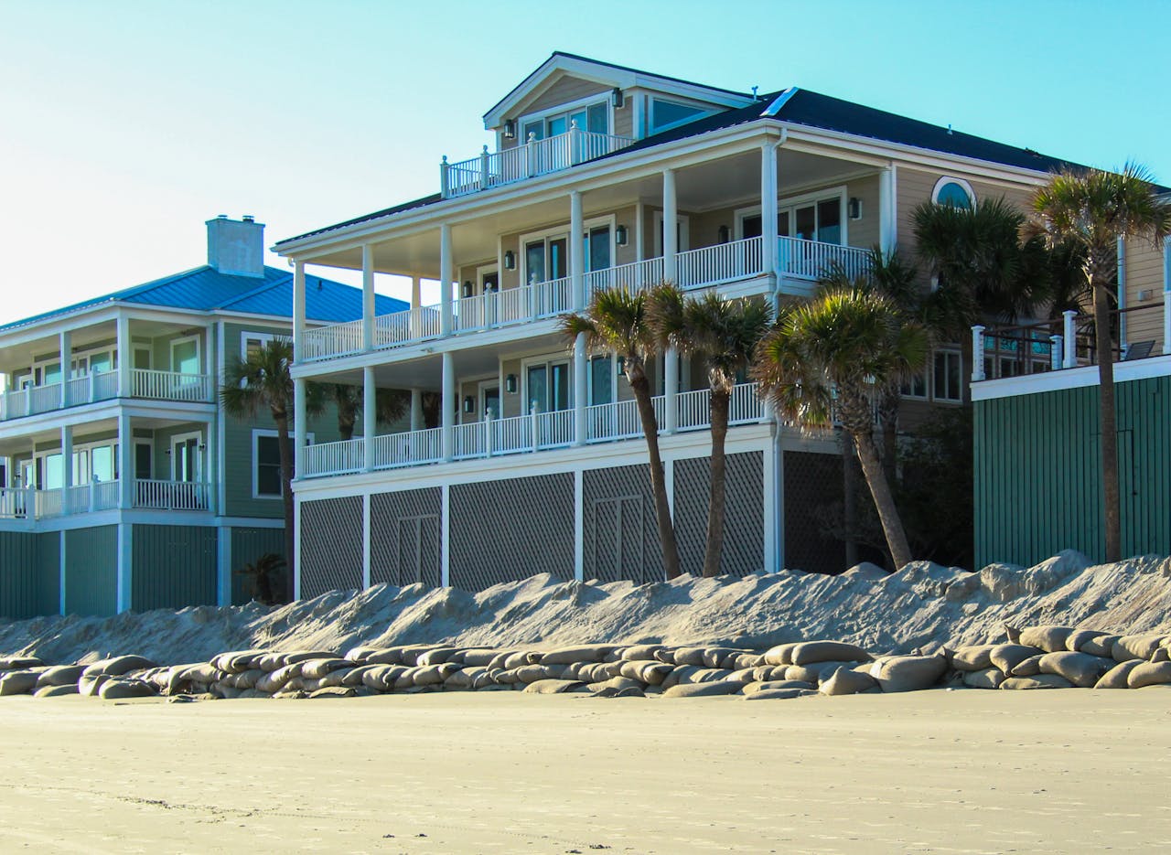Contemporary beachfront villas with palm trees lining the sandy shore under a clear sky.
