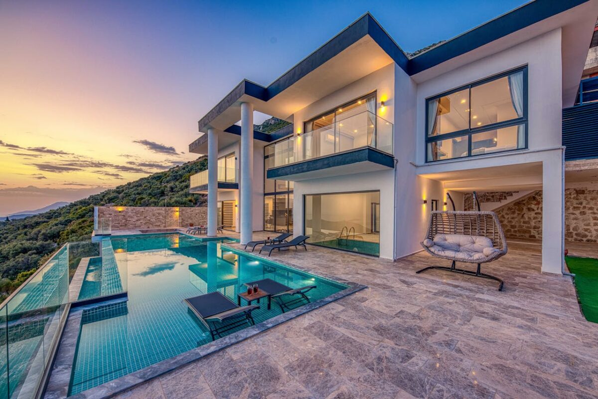 Elegant modern villa featuring an infinity pool and scenic hill views during sunset.