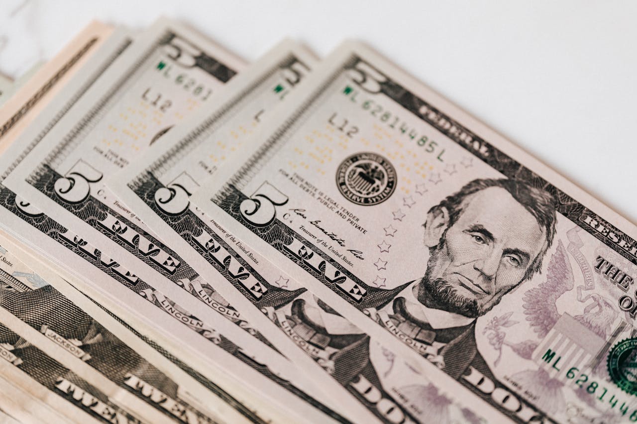 High-quality image of five dollar bills in a neat stack, representing currency and financial concepts.